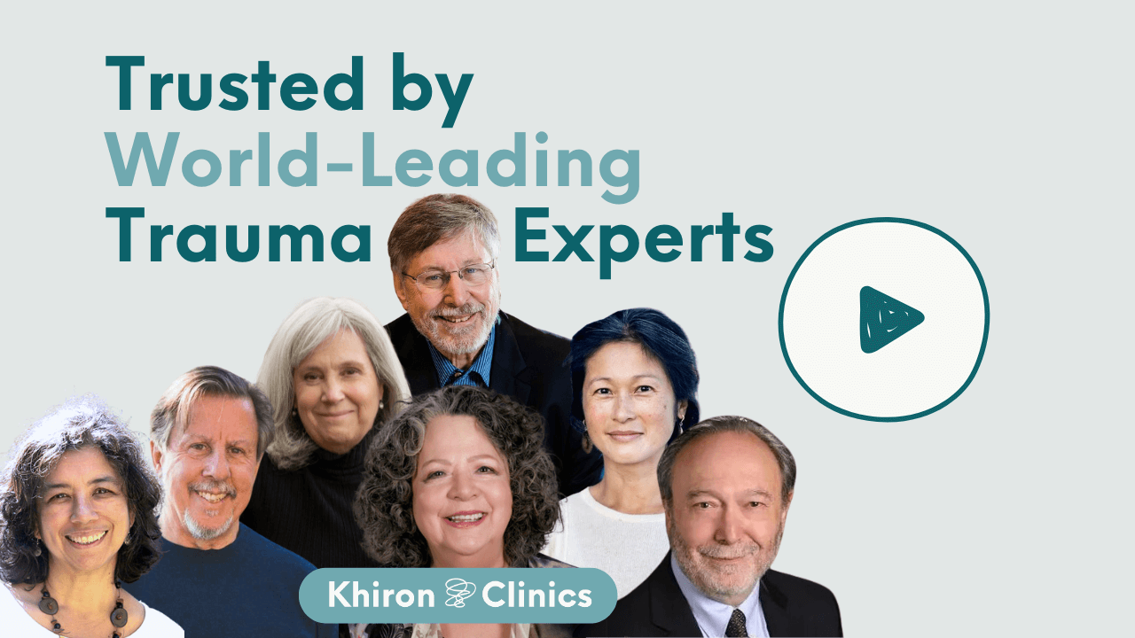 A group photo of seven smiling people beneath the text "Trusted by World-Leading Trauma Experts." To the right is a play button icon; below the group is a Khiron Clinics logo. Discover "What is Trauma" with these leading professionals.