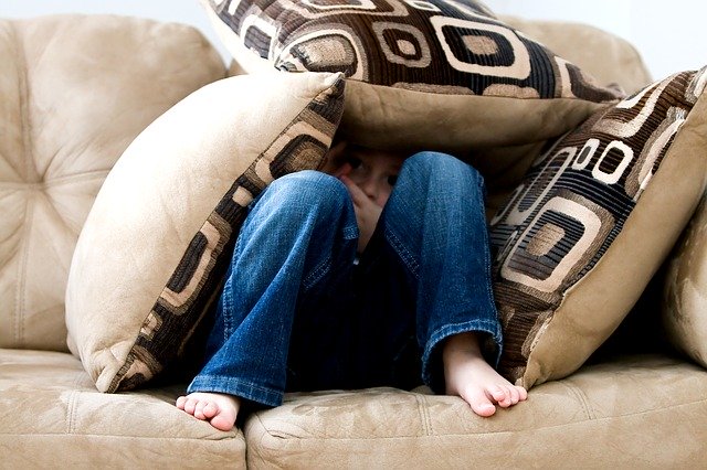 fear little boy hiding in cushions