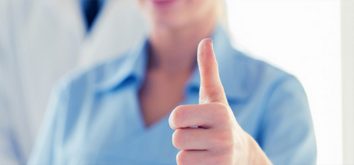 A person wearing a light blue shirt gives a thumbs-up gesture with their right hand. The background is blurred, drawing attention to the hand and gesture in the foreground. The overall mood suggests positivity or approval, signifying hope in mental health treatment or PTSD treatment.