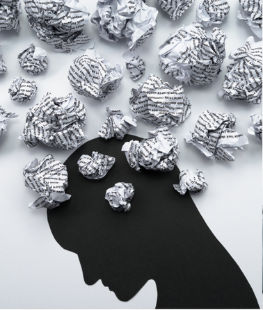 Silhouette of a person's head in profile with crumpled balls of paper emerging from it, symbolizing thoughts or ideas often explored in trauma treatment. The white background contrasts with the black silhouette, enhancing the focus on the scattered paper balls above the head.