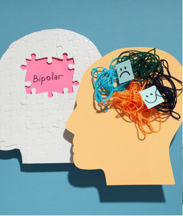 A paper silhouette of a head filled with tangled threads and two sticky notes—one with a sad face, the other with a happy face. Next to it is a puzzle piece labeled "Bipolar Disorder" on a pink background, hinting at mental health and trauma treatment.