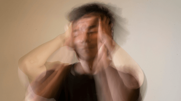 Blurred image of a person holding their head with both hands against a neutral background, suggesting confusion or stress—a visual representation of the challenges addressed in "What We Treat.