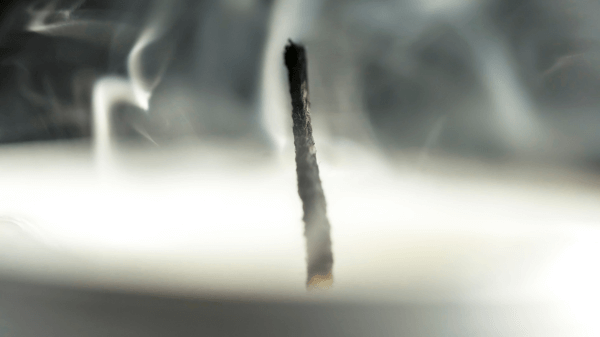 Close-up of a smoking extinguished candle wick surrounded by swirling smoke. The blurred background emphasizes the dark wick in sharp focus, creating a calm, atmospheric scene—much like the focused approach we take in "What We Treat.